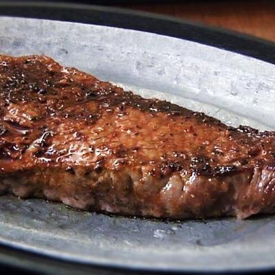 Grilled steak on a metal platter.