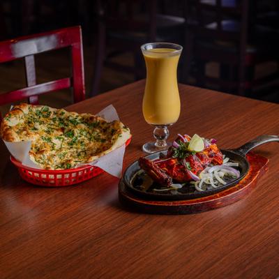 Marinated chicken breast, naan bread with spices, and a drink.