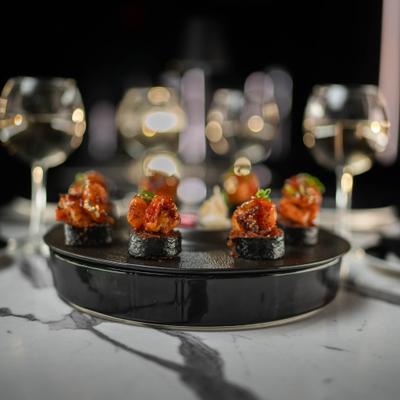 Surf and turf jollof sushi on a black plate.