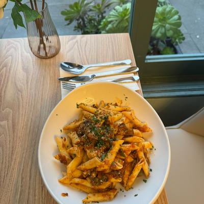 Penne pasta in red sauce on wooden table.