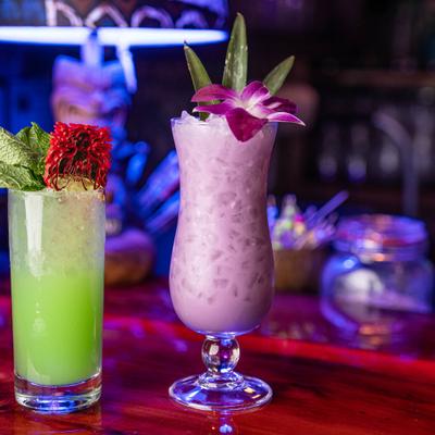 Two colorful cocktails served side by side on the bar.