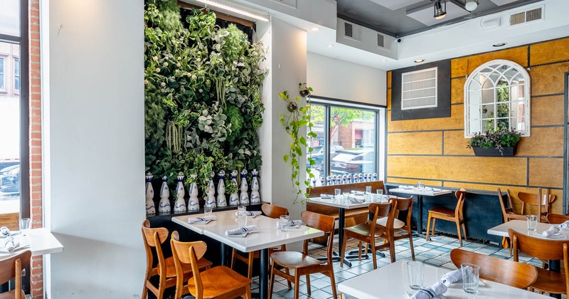 Interior, dining area, tables with chairs ready for guests, green wall decoration