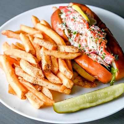 Lobster sandwich served with seasoned fries and a pickle spear.