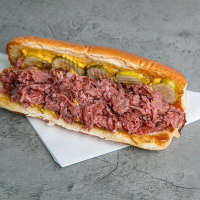 Pastrami sandwich with mustard and pickle.