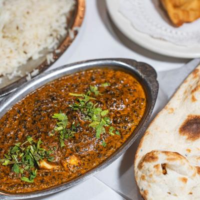 Paneer curry garnished with cilantro served with naan and basmati rice.