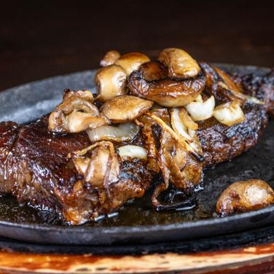 Sizzling Steak topped with mushrooms, served in a skillet.