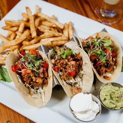 Chicken tacos served with sour cream, guacamole, and french fries