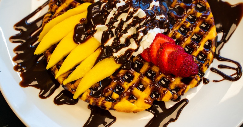 Fruit waffle topped with whipped cream and drizzled with chocolate sauce