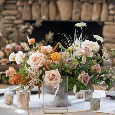 Wedding table centerpiece with floral display, a stone fireplace is in the background