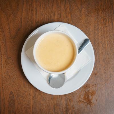 Lobster Bisque served in a white bowl atop a white saucer with a metal spoon.