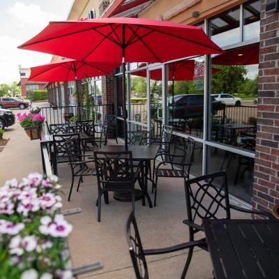 Storefront featuring outdoor seating area with tables, chairs and umbrellas.