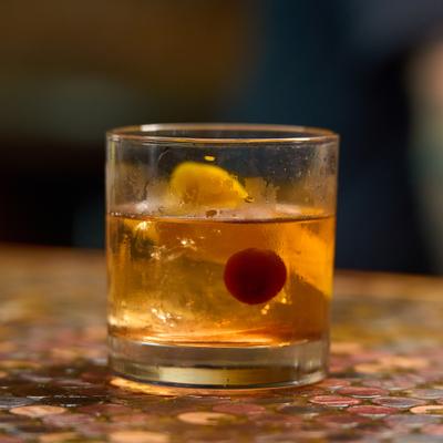 Old Fashioned cocktail garnished with orange peel and a cherry.
