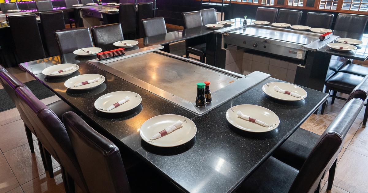 Japanese hibachi style interior dining area with large teppanyaki grill tables set for guests