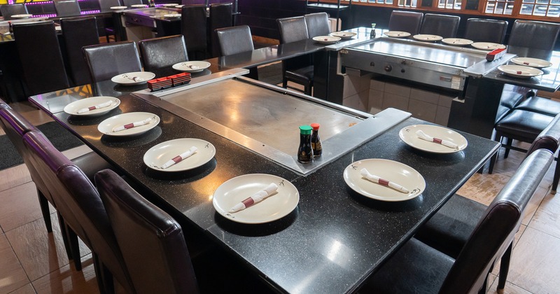 Japanese hibachi style interior dining area with large teppanyaki grill tables set for guests
