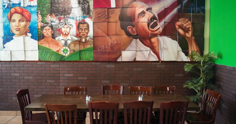 Interior, large table with chairs in front of wall with paintings