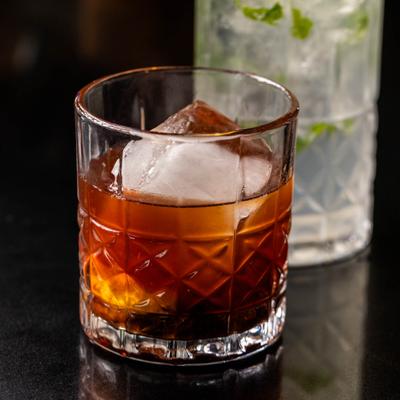 Old Fashioned cocktail served over large ice cube.