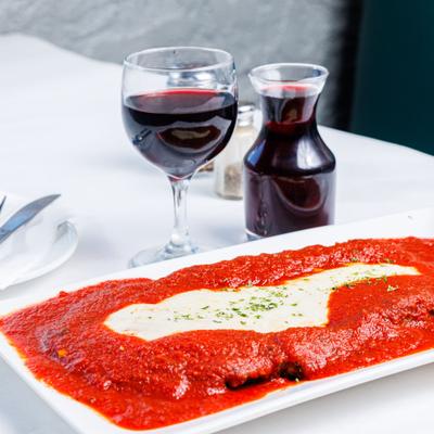 Veal Parmesan dish with small decanted and glass of red vine.
