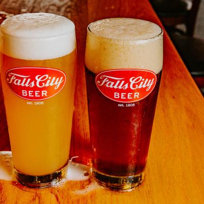 Two pint glasses of Falls City Beer, one light amber, one dark amber..