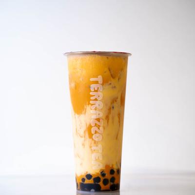 A tall clear cup of vibrant orange bubble tea.