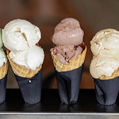 Four ice cream cones in a stand, featuring mint chocolate chip, vanilla, chocolate and caramel flavors.