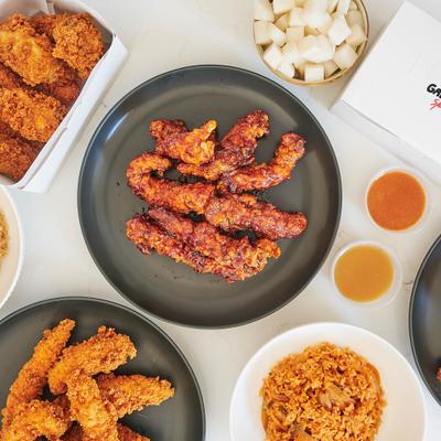 Crispy Korean fried chicken tender strips with dipping sauces, Korean pickled radish, and other Korean food.