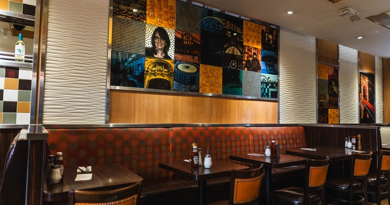 Restaurant interior with booths and a collage of framed artwork on the wall above