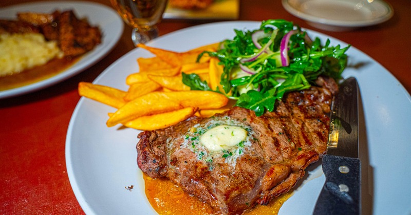 A meal of steak and frites served with a small arugula salad with sliced red onion