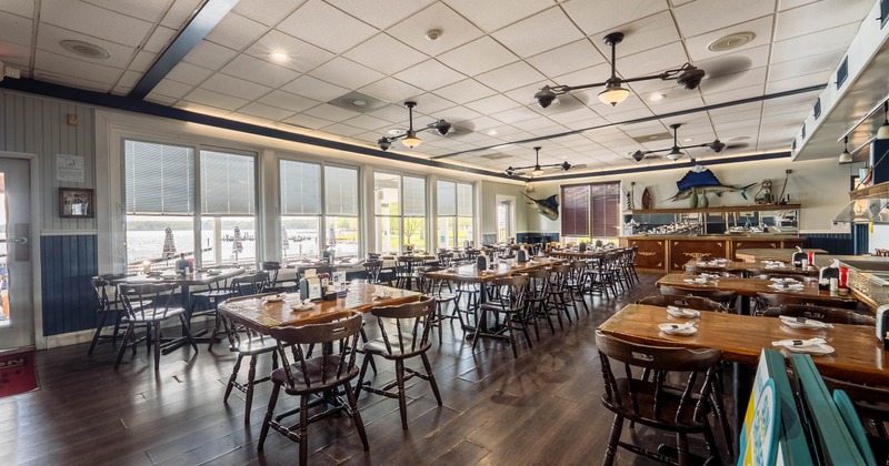 Interior of a nautical-themed restaurant with wooden tables and chairs, large windows