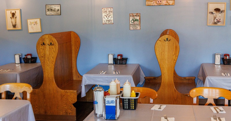 Interior of a restaurant featuring wooden booths, tables with white tablecloths