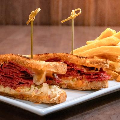 Reuben sandwich served with a side of french fries.