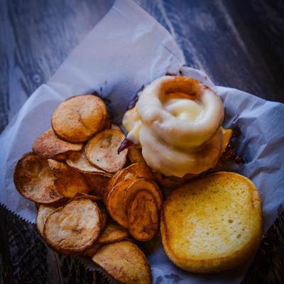 Bacon cheeseburger with onion rings, and a side of chips.