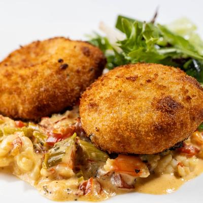 Crab cakes served over bell pepper and cheese macaroni with green salad.