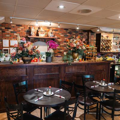 Interior featuring a wooden bar counter with floral arrangements and table seating.