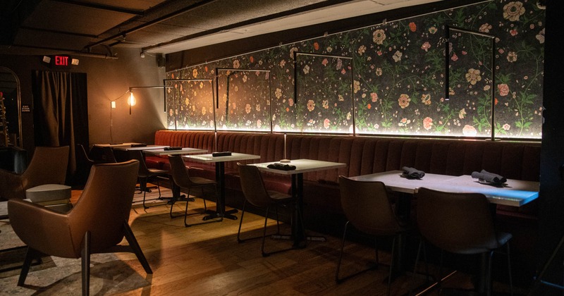 A dimly-lit restaurant interior with burgundy seating