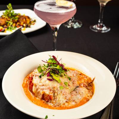 Stuffed pepper in a creamy sauce served with a cocktail.
