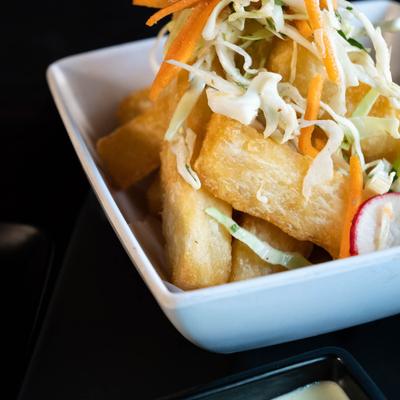Fried yucca topped with shredded carrots and cabbage, close-up.