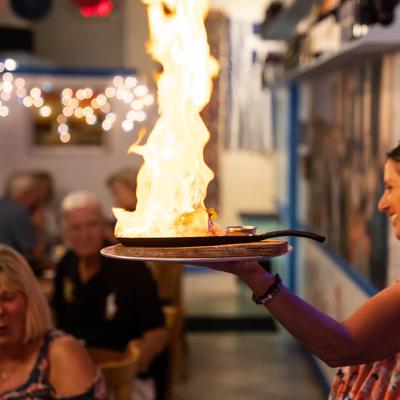 Server shows guests a plate with a dish aflame