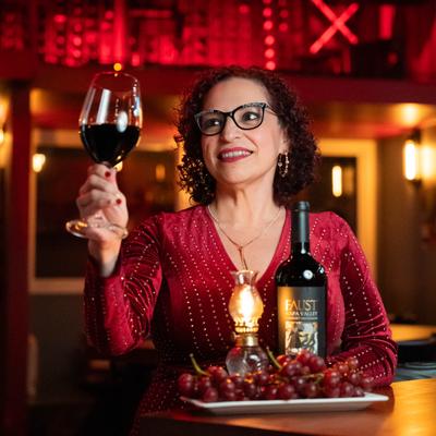 A smiling person with red wine.