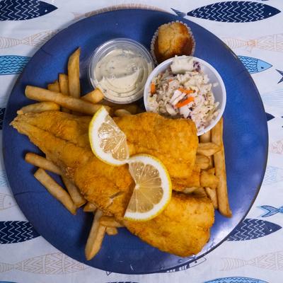 Fish and chips served with fries, coleslaw, tartar sauce, and a corn muffin.