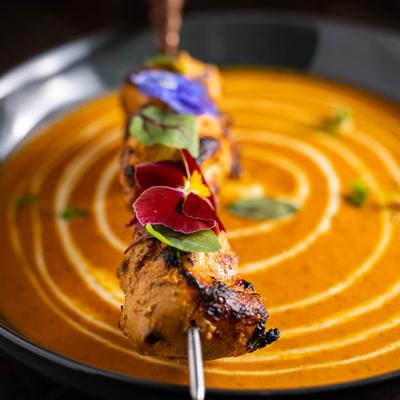 A dish with curry and smoked chicken on a skewer