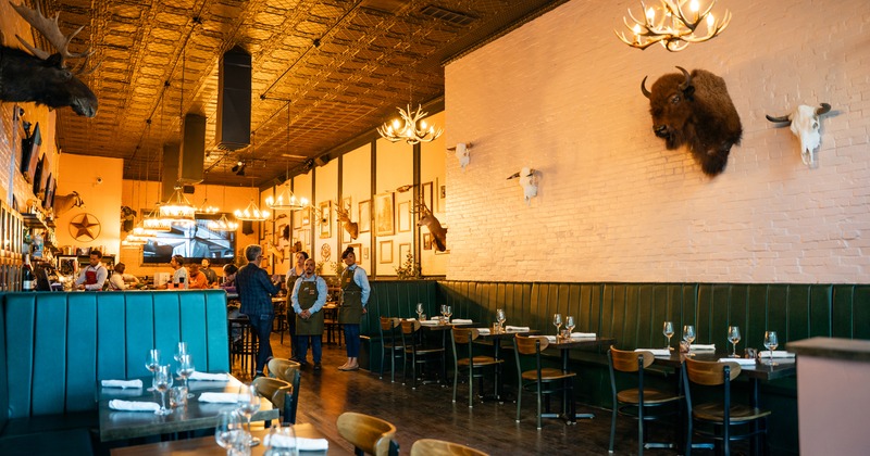 Modern rustic-style restaurant interior dining area with set tables and a bar area at the back