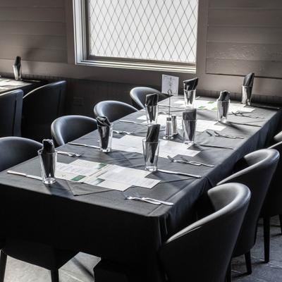 Black tablecloth dining setup with polished glassware beside a sunlit window.