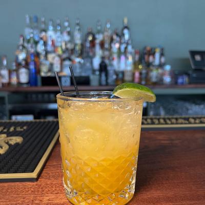 Yellow cocktail with a lime wedge.