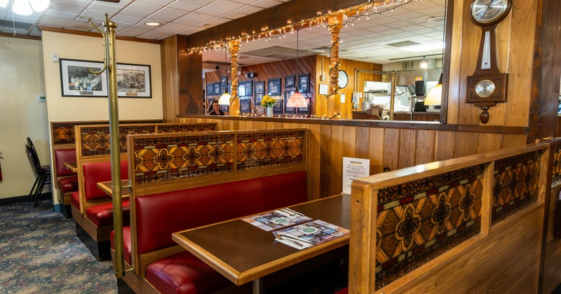 Interior of a cozy restaurant featuring red booths with decorative backs