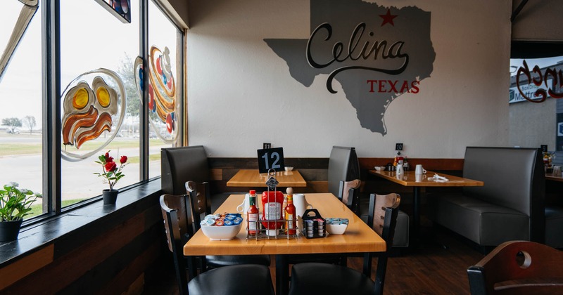 Interior, table for four in front, seating booths with tables in the back, shop window