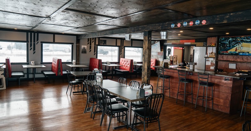 A cozy restaurant interior with wooden floors, tables, and red cushioned booths
