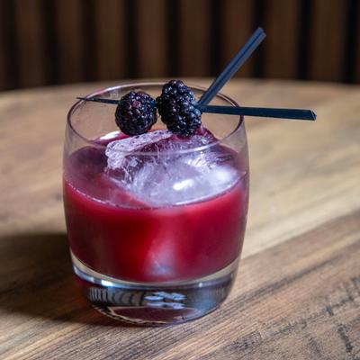 Berry cocktail served on the rocks with blackberry garnish.