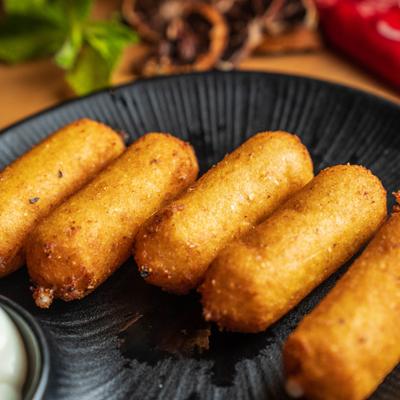 Tequenos de Cachapa arranged on a black plate.