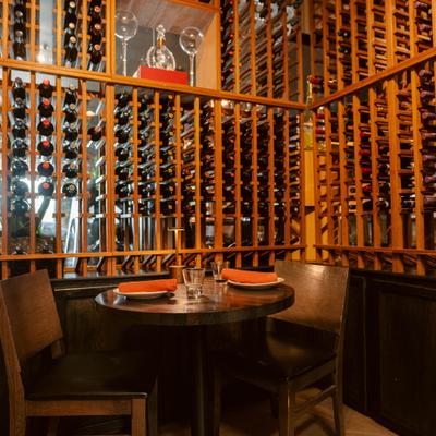 Intimate dining table surrounded by wooden wine racks and bottle displays.