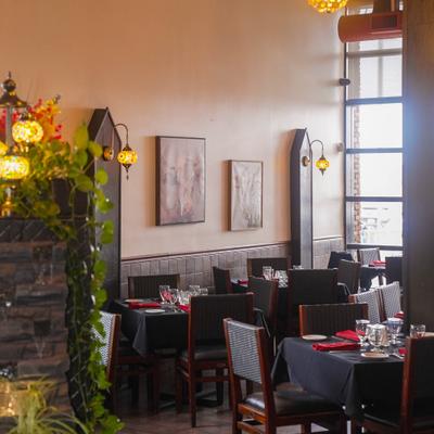 Dining room with set tables, wall-mounted mosaic lamps and framed artwork.